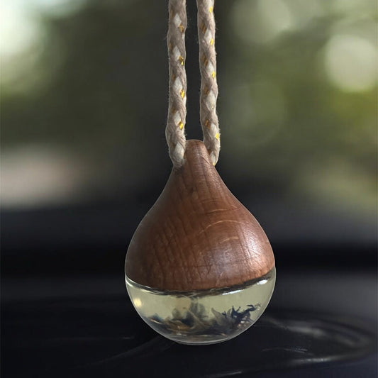 Decorative hanging car diffuser suspended from a rearview mirror, infused with premium essential oils, available in White Tea, Lemon Lavender Mint, Love Spell, and Energy scents for a fresh and calming driving experience.