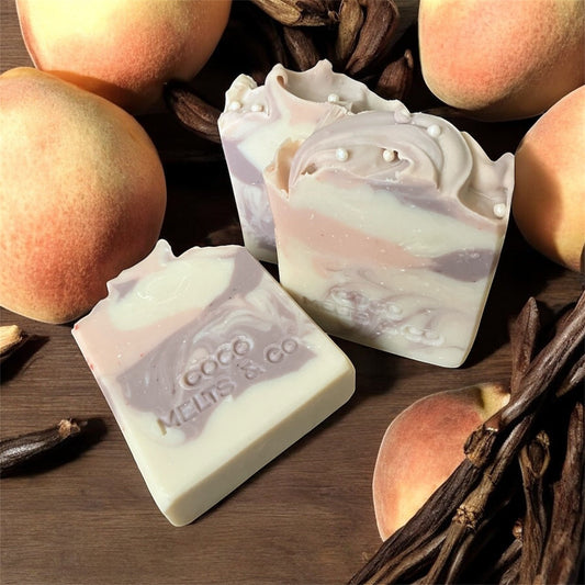 Handmade coconut-free bar soap with natural purple, pink, and white clay swirls, enriched with shea butter and mango butter, with a sweet peach vanilla scent